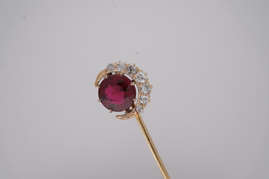 An early to mid 20th century yellow metal and single stone garnet topped doublet set stick pin, with diamond set crescent border, 61mm, gross weight 2.9 grams. Condition - fair to good